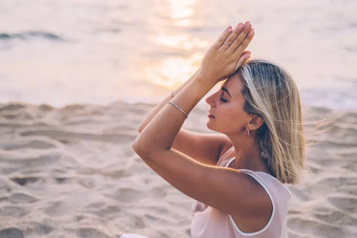 Woman Focusing during doing Yoga at beach for better health of both mind and body.
