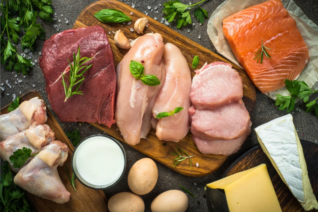 Fish, egg, meat, and milk on a wooden cutting board.